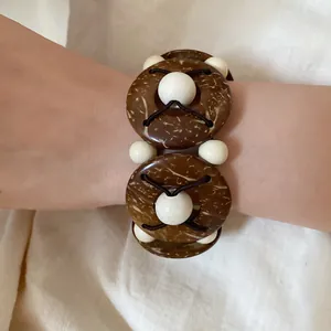 Dettaglio di un braccialetto etnico con gusci di cocco marroni e perline di legno chiaro