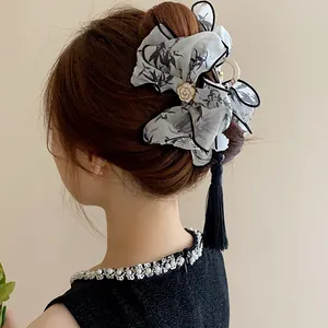 Vista posterior de elegante pinza de pelo de tela estilo chino con borla en moño