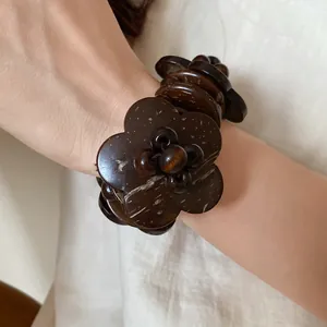 Dettaglio di un braccialetto etnico in guscio di cocco marrone scuro con fiori a perline