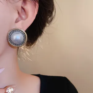 Primo piano di un orecchino vintage a lobo con perla sintetica e bordo metallico intrecciato
