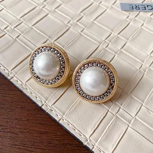 Vista macro di orecchini vintage con perle finte rotonde con finitura oro e argento