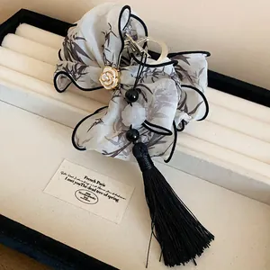 Detalle de pinza para el pelo con lazo de estilo francés, flor de camelia y borla negra