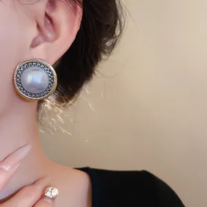 Primo piano di un orecchino a perno vintage rotondo in finta perla con bordo elegante