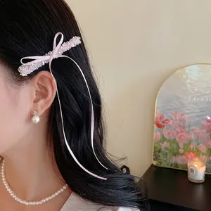 Barrette à nœud rose avec perles en verre et long ruban sur les cheveux du mannequin