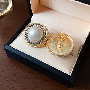 Dettaglio ravvicinato di orecchini vintage con perle, bordo in metallo e retro in scatola