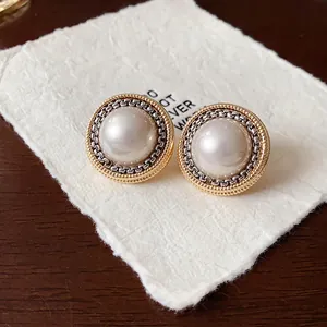 Primo piano di orecchini vintage con perle finte e bordi testurizzati in oro e argento.