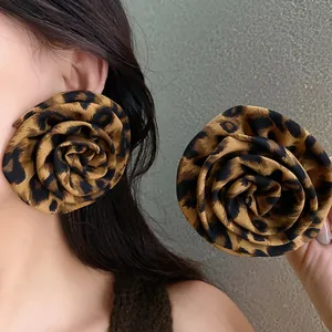 Dettaglio di orecchini a rosa in tessuto leopardato oversize su una modella