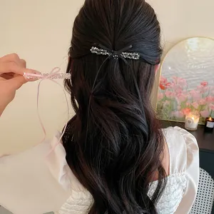 Vue détaillée d'une barrette à perles de verre avec nœud en ruban sur les cheveux.