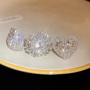 Primo piano di tre scintillanti anelli in argento con strass a forma di quadrato, cuore e sole.