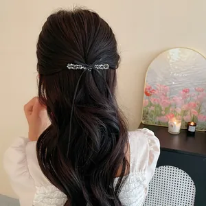 Élégante barrette à nœud en perles de verre noires sur de longs cheveux ondulés