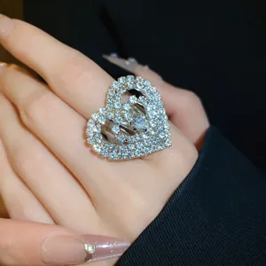 Primo piano di un anello oversize a forma di cuore con strass bianchi scintillanti.