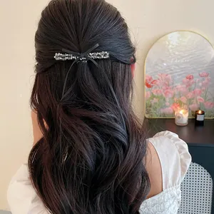 Vue détaillée d'une barrette à cheveux décorée de perles de verre et d'un nœud noir.