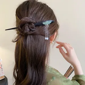 Close-up view of a vintage Chinese style wooden hair stick with jade butterfly and tassels