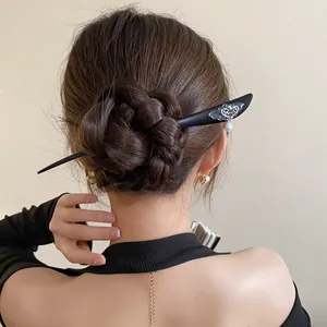 Detail of elegant wooden butterfly hair stick with pearl tassel styled in a hair bun