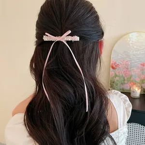 Vue détaillée d'une barrette à nœud rose avec perles de verre et longs rubans élégants