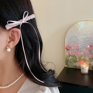Vue détaillée d'une pince à cheveux à nœud rose avec perles de verre sur les cheveux d'un modèle