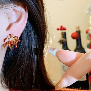 Close-up detail of red firework stud earrings with zircon accents and 18K gold plating.