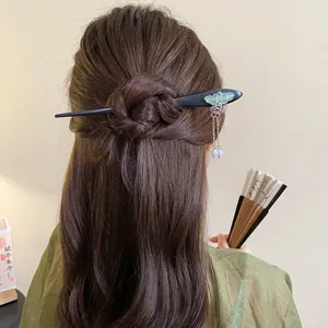 Close-up of an elegant wooden butterfly hair stick with tassels on a Chinese-style bun.