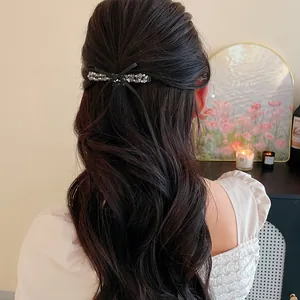 Pince à cheveux noeud avec perles de verre sur les cheveux bouclés d'un modèle