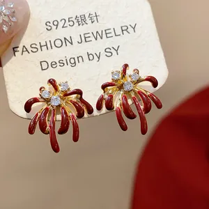 Close-up detail of elegant red firework stud earrings with shiny zircons on a jewelry card