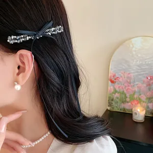 Détail d'une pince à cheveux en perles de verre avec un long ruban noir sur les cheveux