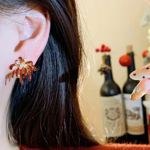 Elegant red fireworks-shaped stud earrings with zircon inlay shown on ear detail