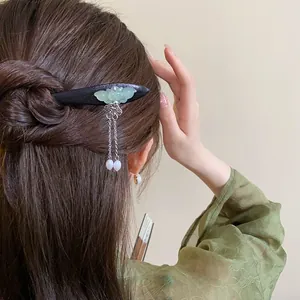 Close-up view of a traditional wooden butterfly hair stick with elegant tassel on hair