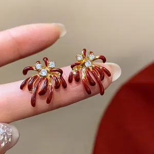 Macro detail view of elegant firework stud earrings with red enamel and zircon accents