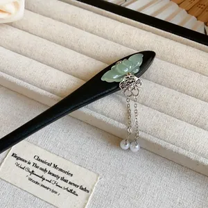 Detailed view of a wooden hair stick with carved jade and dangling pearl tassels