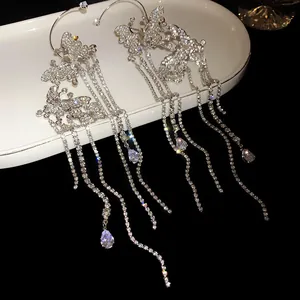 Detailed macro view of shimmering zircon butterfly tassel ear cuffs on a white tray