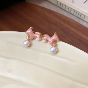 Close-up van zoete roze pony oorknopjes met parels en fonkelende zirkonia details.
