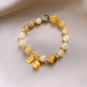 Dettaglio di un bracciale vintage in perle di pietra del sole e agata con ciondoli
