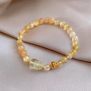 Macro di un bracciale in cristallo di pietra del sole dorata con ciondolo intagliato su raso