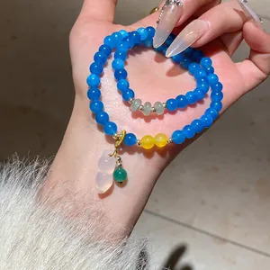 Vista dettagliata dei braccialetti in agata blu con ciondolo hulu e perline gialle accento