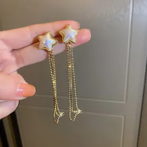 Close-up of elegant star-shaped tassel earrings with rhinestones and pearl inlay.