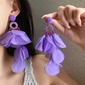 Orecchini a nappa con petali di tessuto viola vibrante mostrati sulla modella
