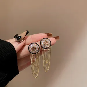 Detailed macro view of elegant gold tassel drop earrings featuring sparkling zircon studs