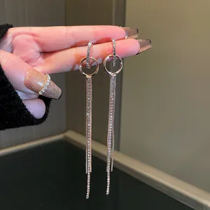 Close-up detail of sparkling long rhinestone tassel dangle earrings held between fingers