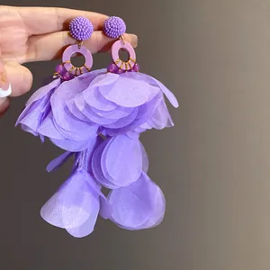 Dettaglio di eleganti orecchini con nappe a petalo di tessuto viola per le vacanze.