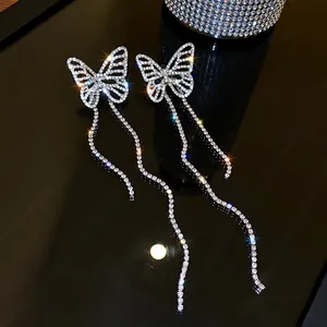 Macro detail of long dangling butterfly earrings adorned with shimmering crystal rhinestones