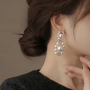 Detailed close-up of elegant French-style pearl and zircon drop earrings on an Asian model