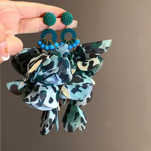 Dettaglio di orecchini bohémien con nappe a petali in tessuto leopardato.