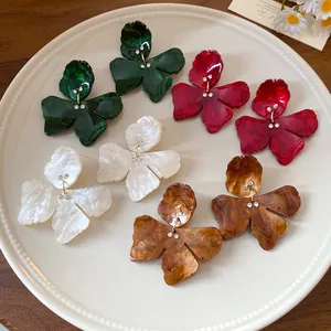 Detail of resin flower earrings in green, red, white, and amber colors with rhinestones