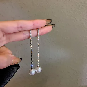 Detail view of long silver tassel earrings with sparkling rhinestones and white pearls