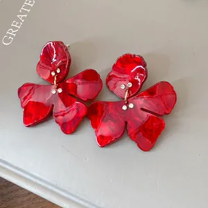 Close-up detail of red floral resin earrings with sparkling rhinestone accents for women