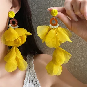 Vista dettagliata degli orecchini con nappe a petali in tessuto giallo vibrante stile boho.
