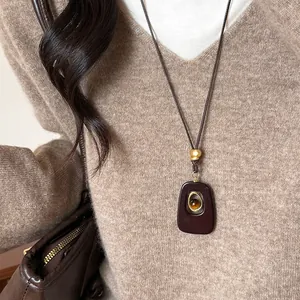 Collar retro con colgante ovalado de ojo de tigre y cordón marrón sobre suéter de punto