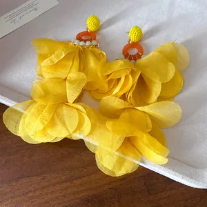Dettaglio degli orecchini con nappe a petali di chiffon giallo per un look da spiaggia