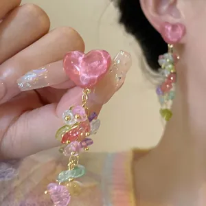 Close-up detail of pink heart-shaped glass earrings with vibrant colorful floral dangles