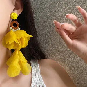 Orecchini a nappa con petali di tessuto giallo, ideali per le vacanze e lo stile estivo.